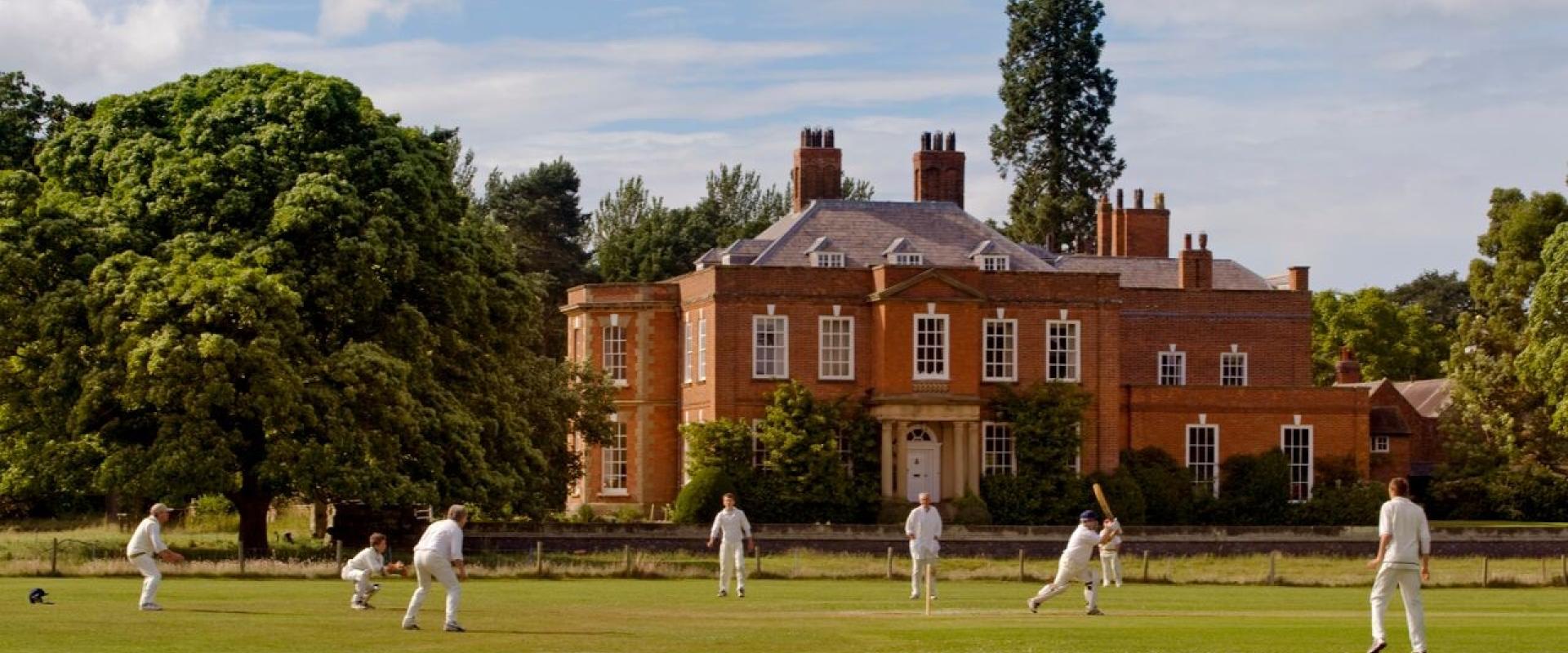 people playing cricket on the grounds in front of Iscoyd Park