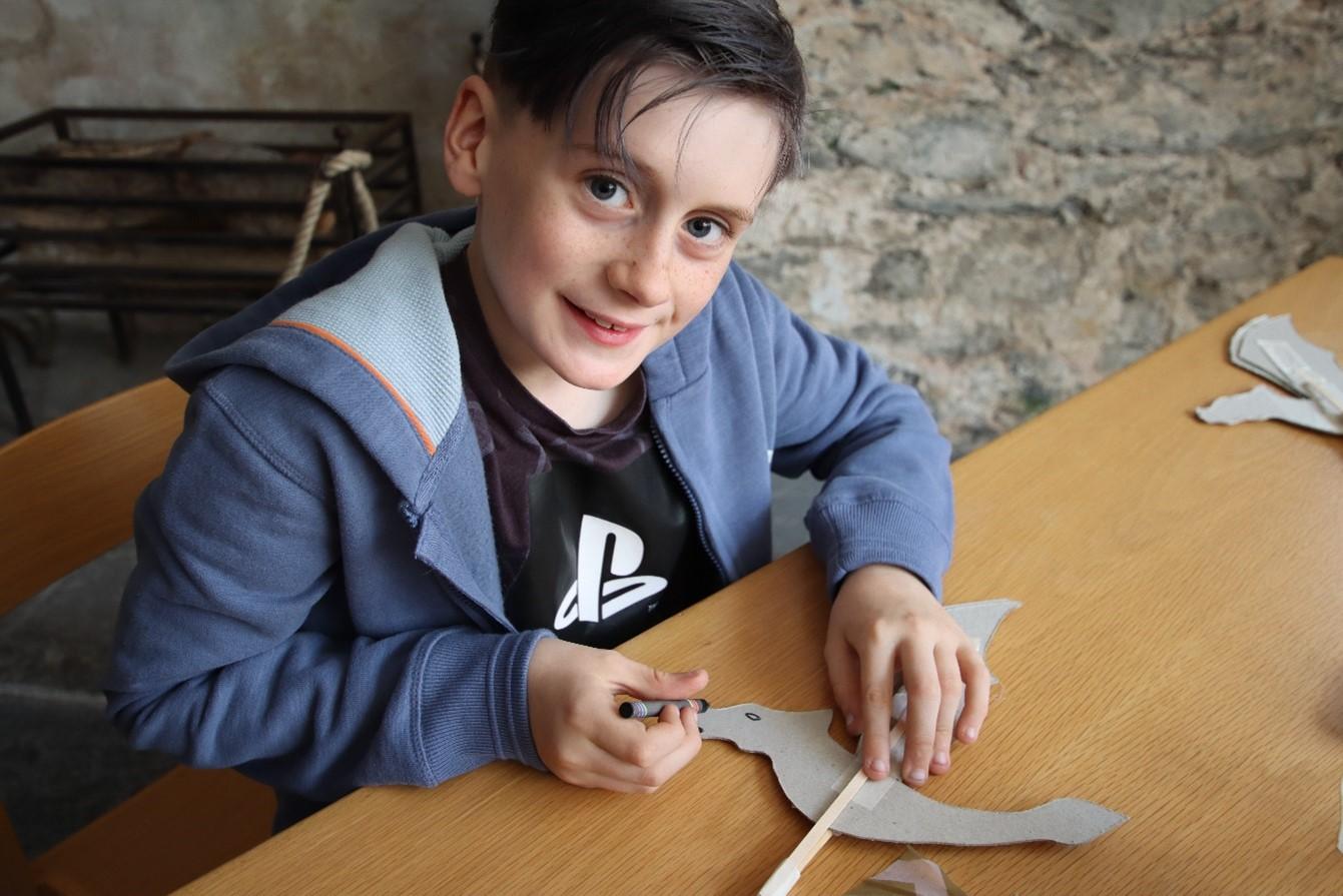 Young boy making a dragon puppet at workshop event